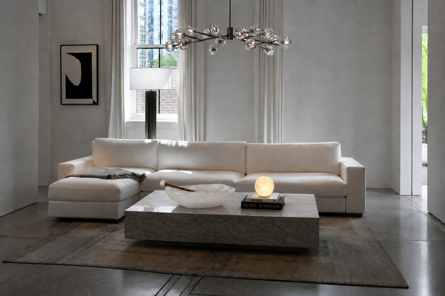 Sala de estar contemporánea con sofá claro y piezas de piedra natural sobre la mesa de centro